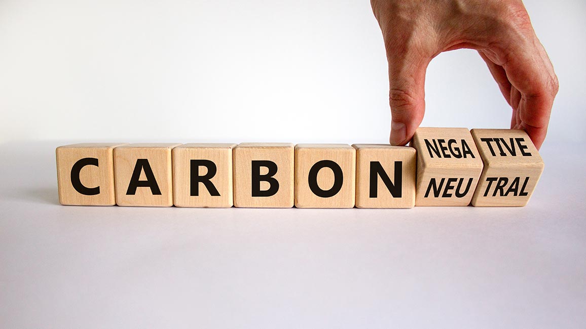 Hand dreht einen Würfel um und ändert die Wörter Carbon neutral in Carbon negativ.